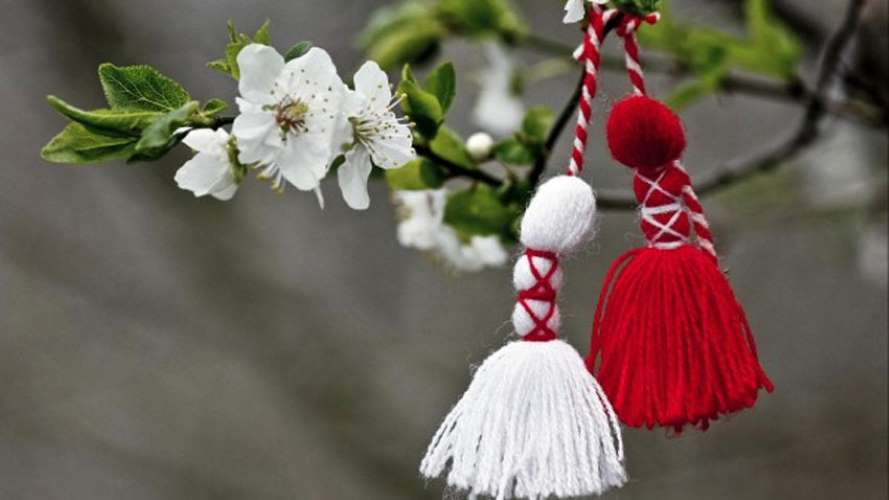 Martenitsis branco e vermelho pendurados em uma árvores